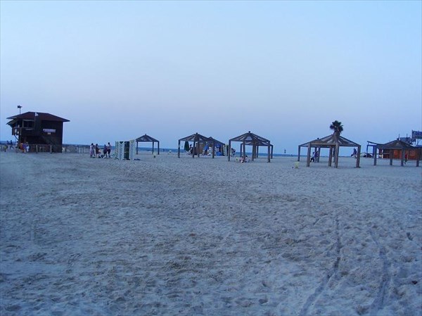 Барышня в красном купальнике отдыхает среди песка