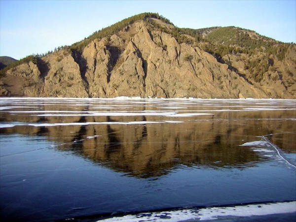 на фото: Высокий берег отражается в застывшей воде как в зеркале