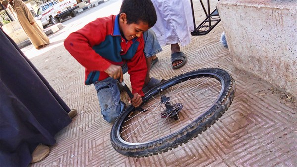 Мальчик помогает накачать колесо